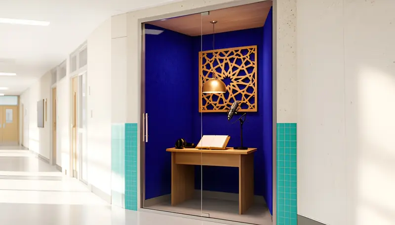 Concept rendering of a small glass-fronted booth lined in deep blue felt, with a wooden desk, an open book on a stand, headphones, a microphone, a warm pendant light and a wooden geometric lattice panel.